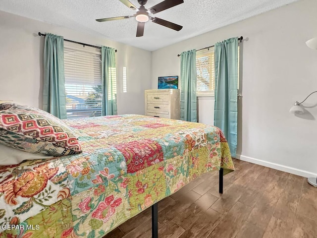 1523 Vista Real Dr, El Paso, TX 79935 - bedroom featuring multiple windows, wood finished floors, a textured ceiling, baseboards, and ceiling fan