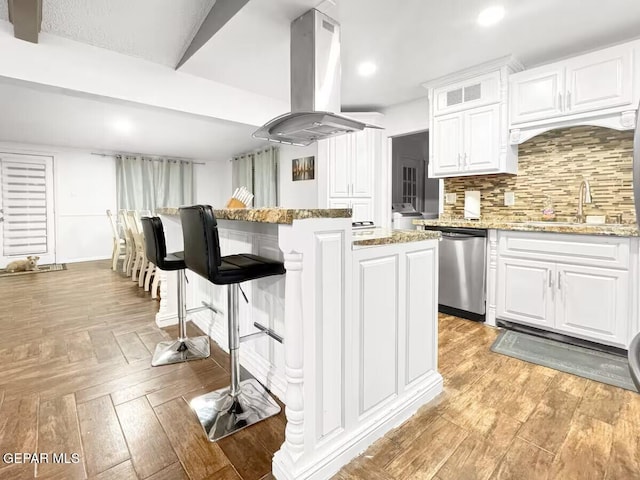 1523 Vista Real Dr, El Paso, TX 79935 - kitchen featuring stainless steel dishwasher, island range hood, white cabinetry, a kitchen bar, and light stone countertops