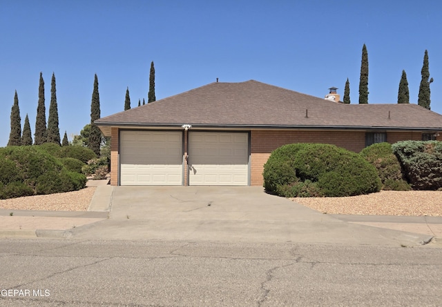 view of side of property featuring brick siding, concrete driveway, and a garage