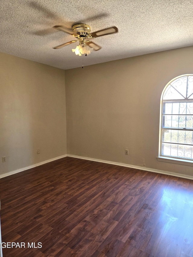 spare room featuring dark wood-style floors, ceiling fan, a textured ceiling, and baseboards