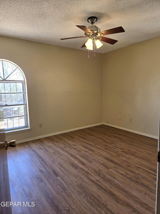 spare room featuring dark wood finished floors, a ceiling fan, a textured ceiling, and baseboards