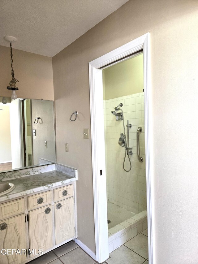 full bath featuring tile patterned floors, vanity, a shower stall, and a textured ceiling
