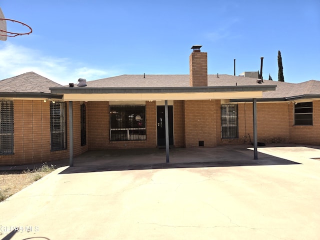back of property with a chimney and brick siding