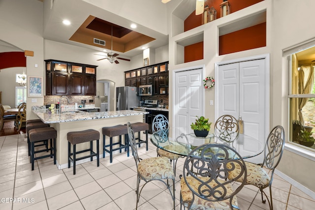 421 Wild Willow Dr, El Paso, TX 79922 - dining area with arched walkways, a towering ceiling, ceiling fan, baseboards, and light tile patterned floors