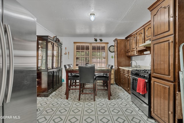 8715 Lawson St, El Paso, TX 79904 - kitchen featuring stainless steel fridge, gas stove, a sink, a textured ceiling, and under cabinet range hood