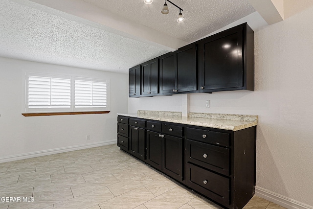 4540 Swan Dr, El Paso, TX 79922 - kitchen with dark cabinets, a textured ceiling, light countertops, and baseboards