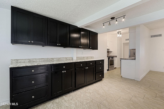 4540 Swan Dr, El Paso, TX 79922 - kitchen with dark cabinets, stainless steel appliances, a textured ceiling, baseboards, and light stone counters