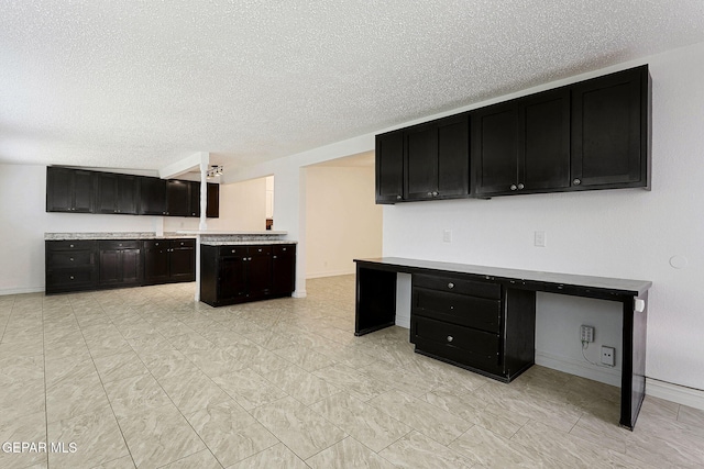 4540 Swan Dr, El Paso, TX 79922 - kitchen with dark cabinetry, a textured ceiling, baseboards, and light countertops