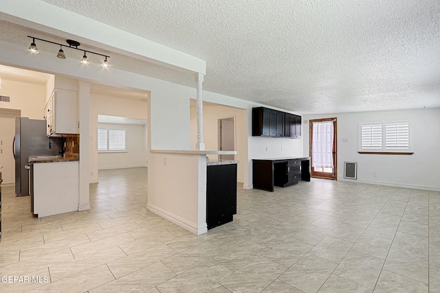 4540 Swan Dr, El Paso, TX 79922 - kitchen featuring a textured ceiling, open floor plan, healthy amount of natural light, light tile patterned floors, and dark cabinetry