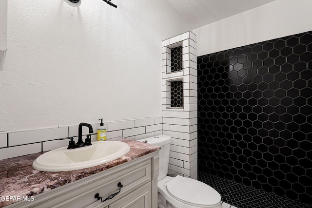 4540 Swan Dr, El Paso, TX 79922 - full bathroom featuring a shower stall, tile walls, toilet, vanity, and a textured wall