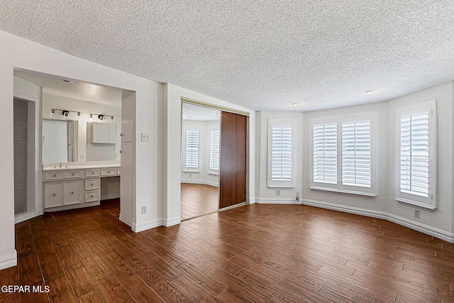 4540 Swan Dr, El Paso, TX 79922 - unfurnished bedroom featuring a textured ceiling, dark wood-style floors, baseboards, a closet, and a sink