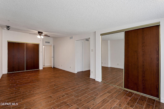 4540 Swan Dr, El Paso, TX 79922 - unfurnished bedroom with dark wood-style floors, a textured ceiling, baseboards, a ceiling fan, and multiple closets