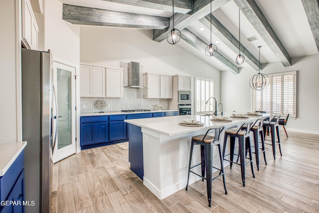 309 Blue Vly, El Paso, TX 79928 - kitchen with stainless steel appliances, wall chimney range hood, blue cabinetry, a sink, and a kitchen breakfast bar