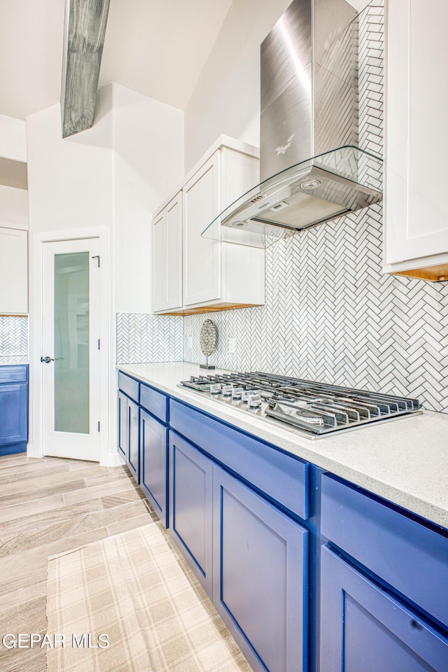 309 Blue Vly, El Paso, TX 79928 - kitchen with wall chimney exhaust hood, blue cabinets, stainless steel gas cooktop, and decorative backsplash
