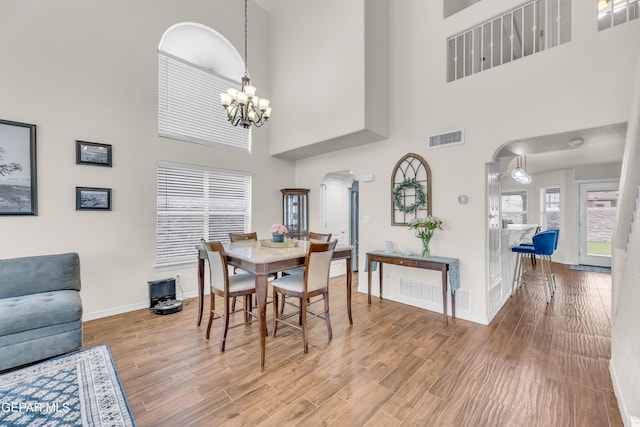 3208 Cascade Point Dr, El Paso, TX 79938 - dining area with arched walkways, a chandelier, wood finished floors, a towering ceiling, and baseboards