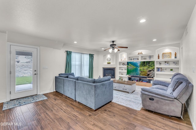 3208 Cascade Point Dr, El Paso, TX 79938 - living area with wood finished floors, a ceiling fan, a glass covered fireplace, built in features, and recessed lighting