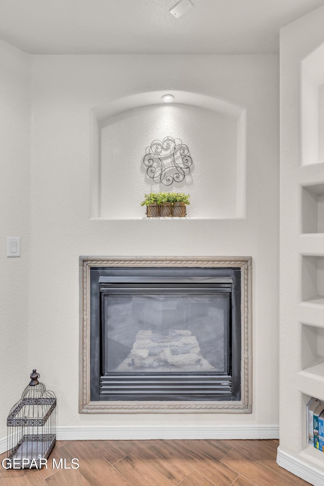 3208 Cascade Point Dr, El Paso, TX 79938 - detailed view of a glass covered fireplace, baseboards, wood finished floors, and built in shelves