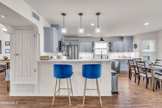 3208 Cascade Point Dr, El Paso, TX 79938 - kitchen featuring stainless steel appliances, open shelves, a peninsula, dark wood-type flooring, and light countertops