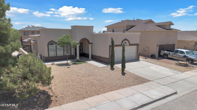 adobe home featuring a garage, concrete driveway, and stucco siding