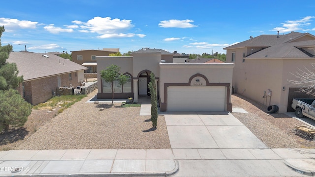 pueblo-style home featuring a garage, driveway, stucco siding, and a residential view