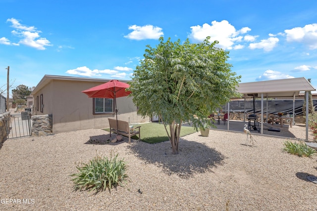 rear view of property with stucco siding, fence, a gate, and a patio area