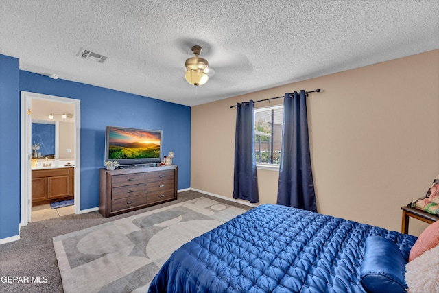 bedroom with light colored carpet, ensuite bath, baseboards, a ceiling fan, and a textured ceiling