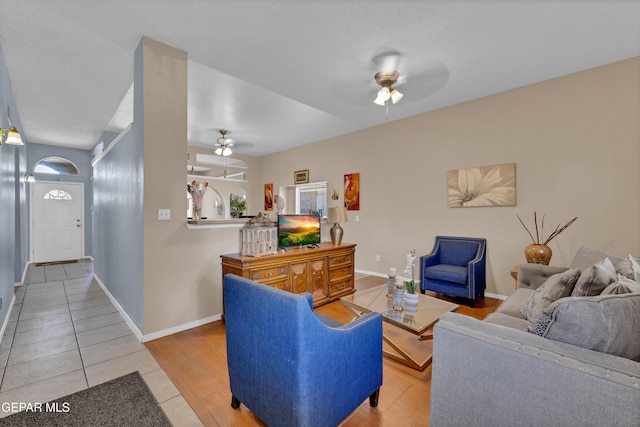 living room with a ceiling fan, tile patterned flooring, and baseboards