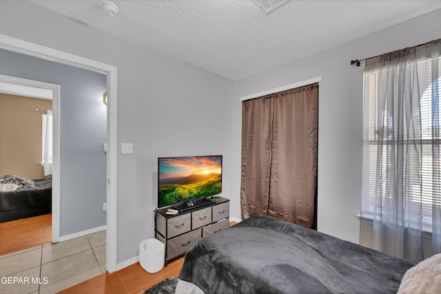 bedroom featuring light tile patterned flooring, a textured ceiling, and baseboards