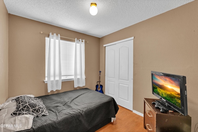 bedroom featuring wood finished floors, a textured ceiling, and a closet