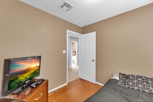 bedroom with wood finished floors, baseboards, and a textured ceiling