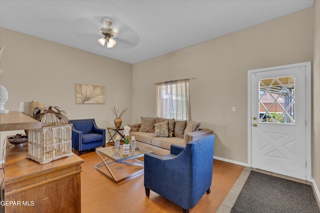 living area with healthy amount of natural light, a ceiling fan, light wood-style floors, and baseboards