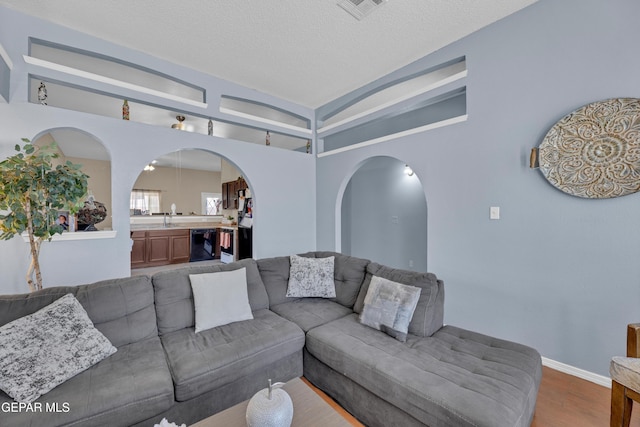 living area with dark wood-style flooring, arched walkways, baseboards, and a textured ceiling