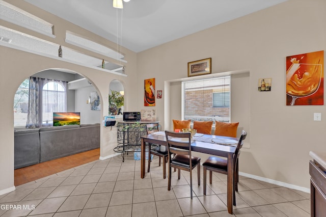 dining area with light tile patterned flooring, baseboards, and arched walkways