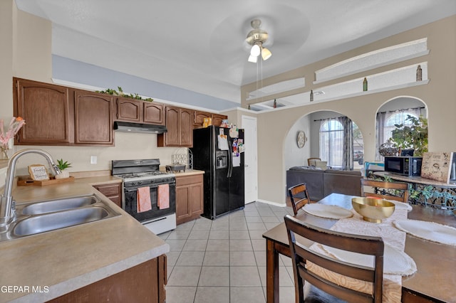 kitchen featuring black appliances, a sink, under cabinet range hood, light countertops, and light tile patterned flooring