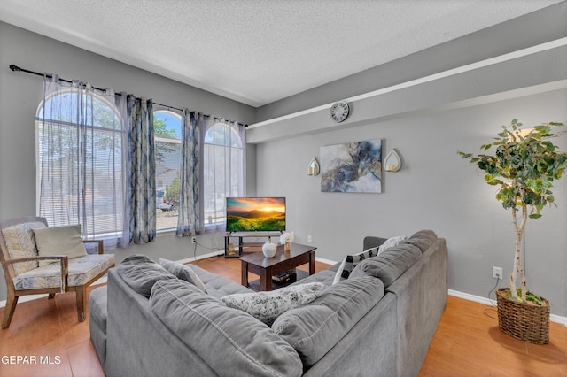living area with light wood-style floors, a textured ceiling, and baseboards