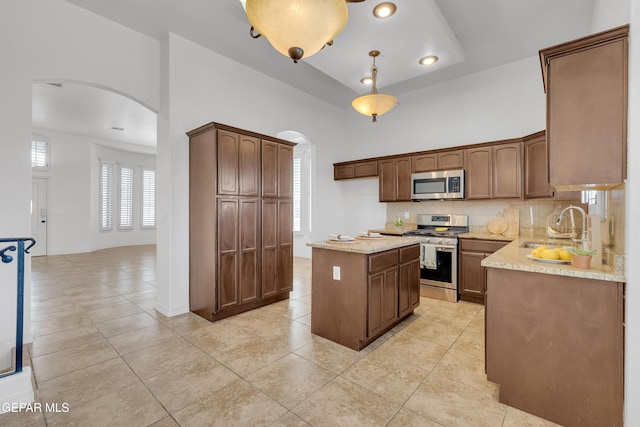 3165 Diego Aidan Dr, El Paso, TX 79938 - kitchen with arched walkways, stainless steel appliances, a sink, light tile patterned floors, and recessed lighting