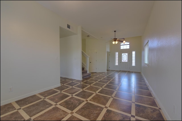 foyer entrance with stairway, a ceiling fan, and baseboards