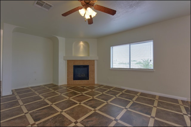 unfurnished living room featuring baseboards, a tiled fireplace, and a ceiling fan