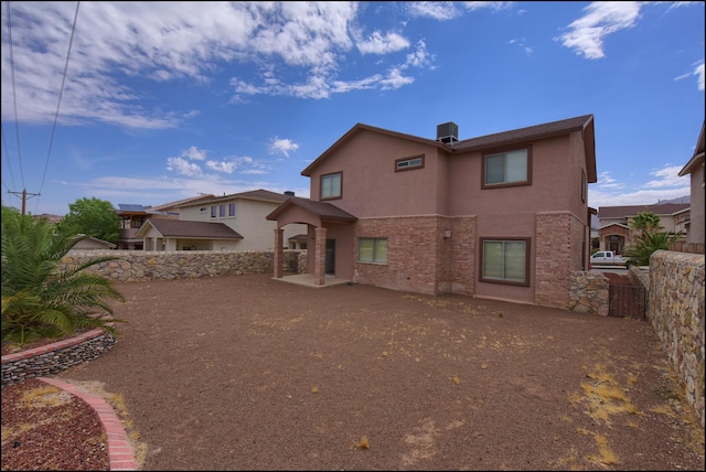 rear view of property with stucco siding, a fenced backyard, a patio, and brick siding