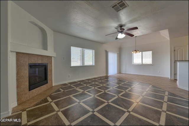 1493 Luz De Sol Dr, El Paso, TX 79912 - unfurnished living room featuring a chandelier, a ceiling fan, a tiled fireplace, baseboards, and a textured ceiling