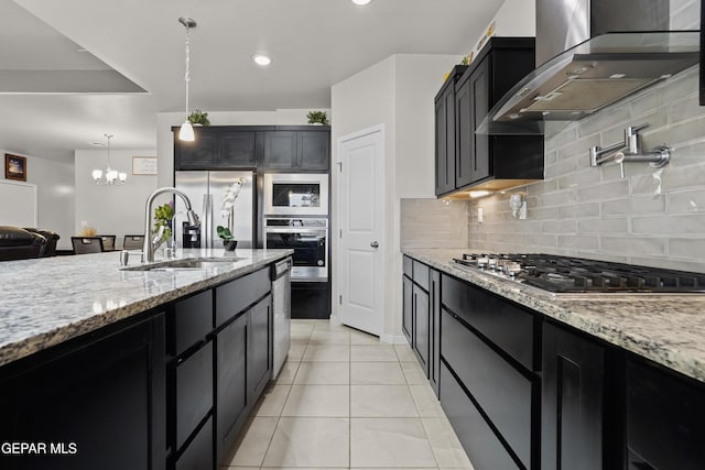 12405 Northumberg Dr, El Paso, TX 79928 - kitchen featuring wall chimney range hood, a sink, appliances with stainless steel finishes, dark cabinetry, and tasteful backsplash