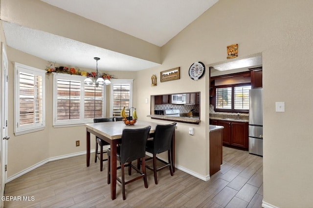 10912 Duke Snider Cir, El Paso, TX 79934 - dining room featuring light wood-style floors, a chandelier, baseboards, and lofted ceiling