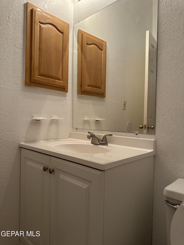 14045 Lago Seco Dr, Horizon City, TX 79928 - half bathroom with vanity, toilet, and a textured wall