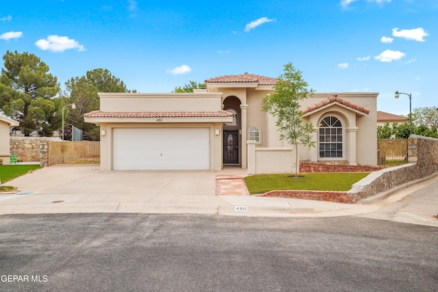 mediterranean / spanish-style house with concrete driveway, a garage, stucco siding, and a tile roof