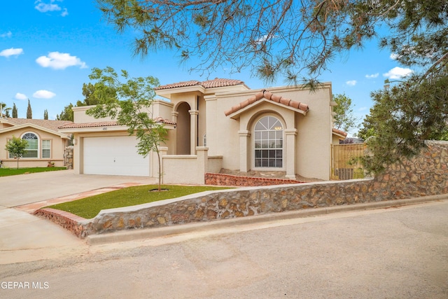 mediterranean / spanish home with driveway, stucco siding, a tile roof, and an attached garage