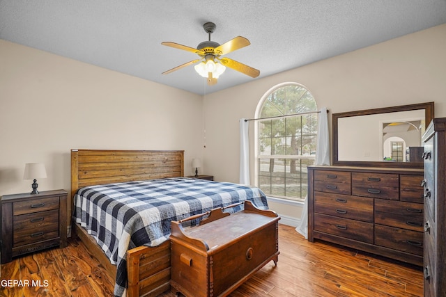 bedroom with wood finished floors, baseboards, ceiling fan, and a textured ceiling
