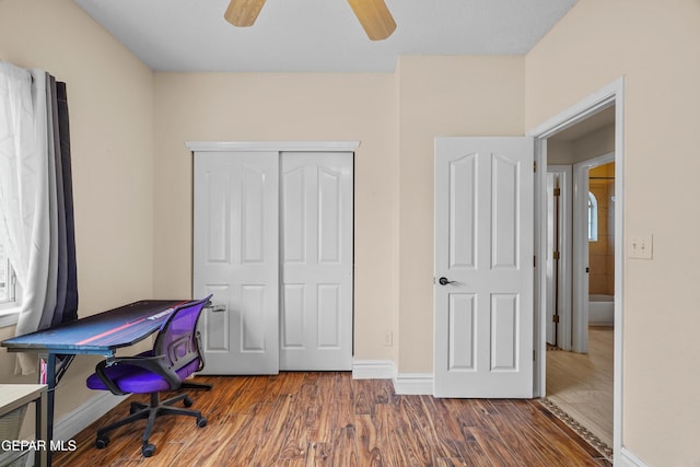 home office with wood finished floors, ceiling fan, and baseboards