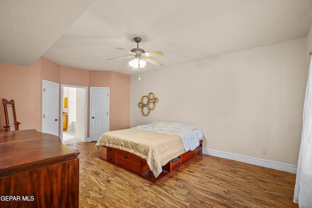 bedroom with wood finished floors, baseboards, ceiling fan, and a textured ceiling