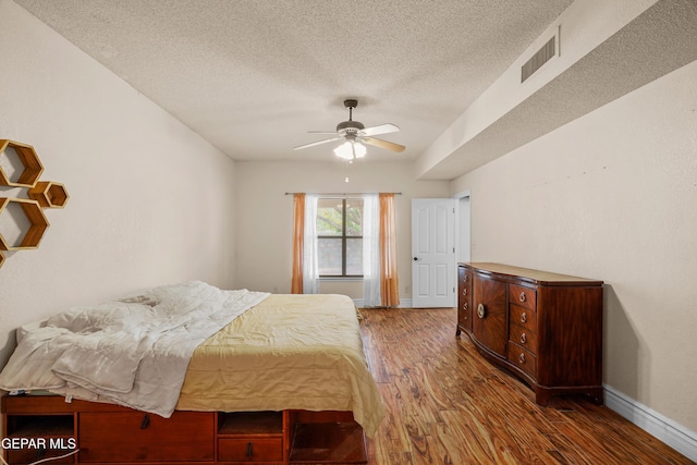 bedroom featuring wood finished floors, a textured ceiling, baseboards, and a ceiling fan