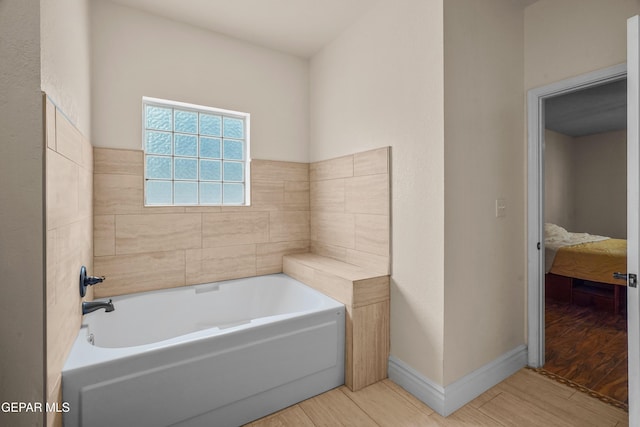 bathroom featuring wood finished floors, a garden tub, and baseboards